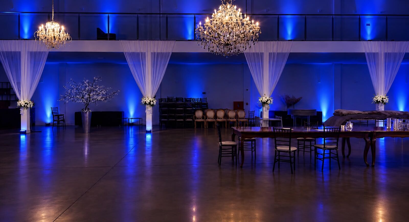 Salão amplo com iluminação azul, lustres de cristal e cortinas